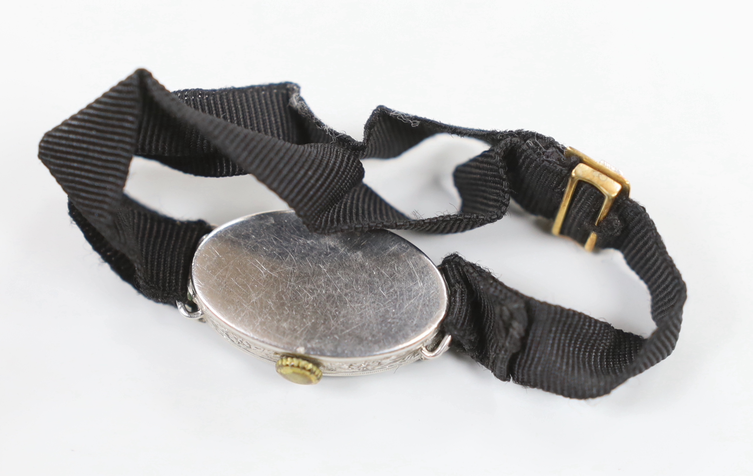 A lady's 1920's/1930's white metal, sapphire and diamond chip set tonneau shaped cocktail watch, on a fabric strap, with sapphire and diamond chip set buckle.